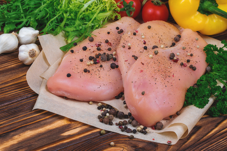 Close up of raw chicken fillet with vegetables and greens on the wooden background.の写真素材