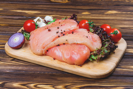 Raw chicken fillet with vegetables and greens on the wooden background.の写真素材