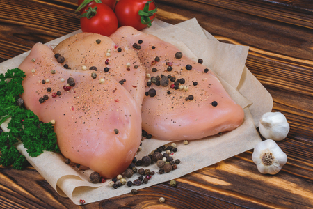Close up of raw chicken fillet with vegetables and greens on the wooden background.の写真素材