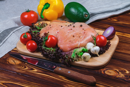 Raw chicken fillet with vegetables and greens on the wooden background.の写真素材