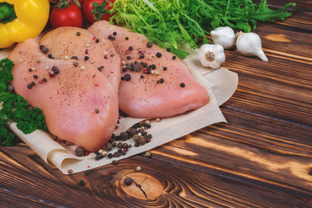 Close up of raw chicken fillet with vegetables and greens on the wooden background.の写真素材