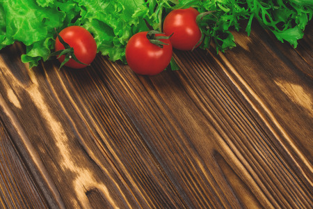 Fresh cherry tomatoes and lettuce on the rustic wooden background. Mock up, copy space for your text.の写真素材