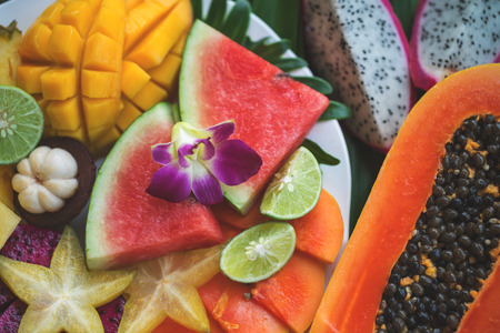 Close up of tropical fruit salad and fresh papaya half. Mix of mango, watermelon, carambola, lime, mangosteen and dragonfruit.の写真素材