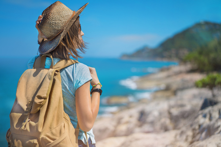 Young european female tourist with a backpack and bamboo cowboy style hat standing on the view point with the scenic beauty landscape. Copy space for your text.の写真素材