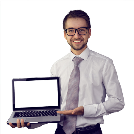 Young smiling business consultant holding laptop with blank white screen. Isolated on white background. Mock up, copy space for your text.の写真素材