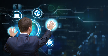 Young businessman touching media graphs on digital screen in virtual office. Futuristic work concept. View from the back. Copy space for your text.の写真素材