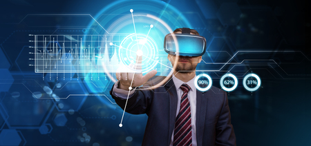 Young businessman working in his futuristic office using virtual reality glasses. Digital screen with financial and media info graphs. Modern business concept.の写真素材