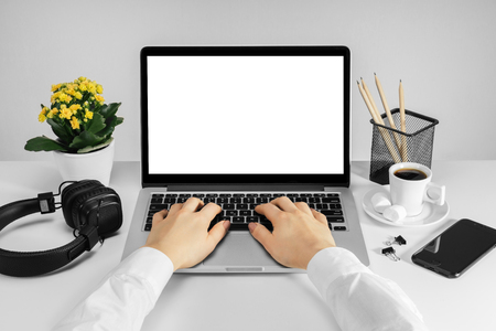 Front view of female hands working on laptop with blank white screen standing on the white office desk. Distant job concept. Mock up, copy space for your text.の写真素材
