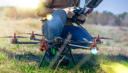 Close up cropped photo of a man sitting near generic design drone doing some adjustments before...