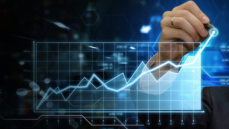 Close up cropped photo of male hand working on digital panel with stylus. Businessman making presentation in his virtual office showing company income progress on financial graph. Futuristic background. Copy space for your text. Business and  finance concept.の写真素材