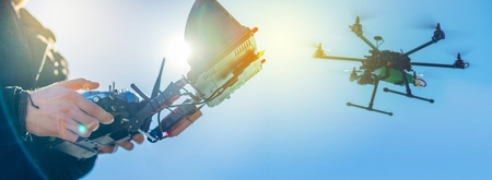 Close up of male hands holding generic design dron remote controller doing some setings ready to run it into the sky. Cropped shot of man adjusting digital telemetry radio system. Active timespending at sunny day. の写真素材
