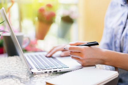 Cropped shot of casual dressed freelancer sitting on her terrace and working using her laptop. Distand work and education in comfortable conditions concept. Horizontal. Copy space for your text.の写真素材