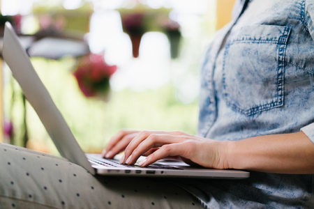Cropped shot of casual dressed freelancer sitting on her terrace and working using her laptop. Distand work and education in comfortable conditions concept. Horizontal. Copy space for your text.の写真素材