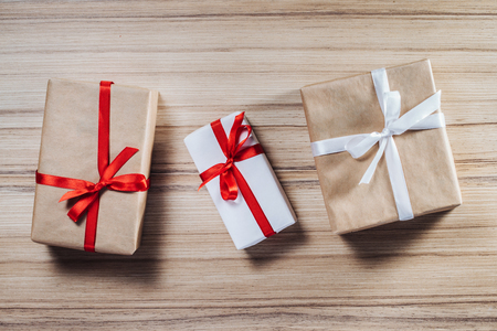 Christmas composition. Top view of three gift boxes wrapped in craft and white paper and decorated with satin ribbons, flat lay.の写真素材