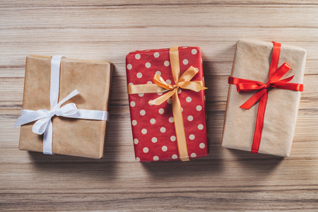 Three gift boxes decorated with satin ribbons on wooden background. Christmas composition. Top view, flat lay. Holiday concept.の写真素材