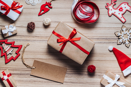 Christmas composition of christmas tree toys, ribbons and decorated gift boxes on rustic wooden background. Blank craft paper tag to write holiday wishes. Mock up, copy space for your text. Top view, flat lay.の写真素材