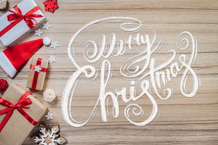 Holiday composition. Border of new year decorarions and gifts on wooden backround with Merry Christmas wishes written with calligraphic font. Top view, flat lay.の写真素材