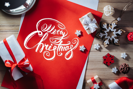 Holiday composition. Border of new year decorarions and gifts on wooden backround with Merry Christmas wishes written with calligraphic font. Top view, flat lay.の写真素材
