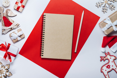 Border of holiday decorations, toys and blank craft paper sketchbook on white background. Mock up, copy space for your text. Christmas composition. Top view, flat lay.の写真素材