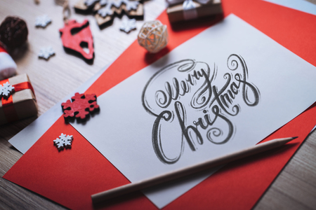 Christmas composition. Closeup of piece of paper with best wishes written with calligraphic font and holiday decorations on wooden desk.の写真素材