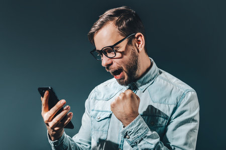 Lucky winner holding fist up celebrating victory after making bets using gambling mobile application...