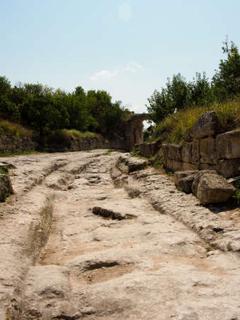 A cave city in the mountains, an ancient stone road with broken ruts from the wheels.の写真素材