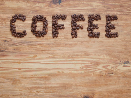 Coffee, the inscription is lined with coffee beans on a wooden background, there is an empty space...