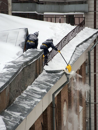 Employees of the municipal service remove snow from the roof of the building, after a heavy snowfall. Working professions, work in the service sector.の写真素材