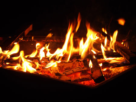 Orange flames on firewood, a dying fire on a dark background. Beautiful close-up background,...