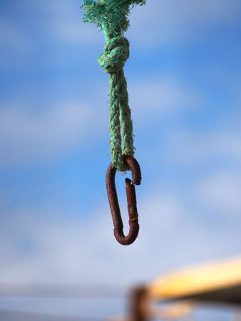 Equipment for lifting light loads, a sling with an old, rusty hook. A rusty object on a blurry background, close-up.の写真素材