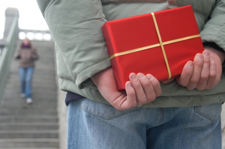Valentine's Day Gift. Young man with a red gift box waiting for a girlの写真素材