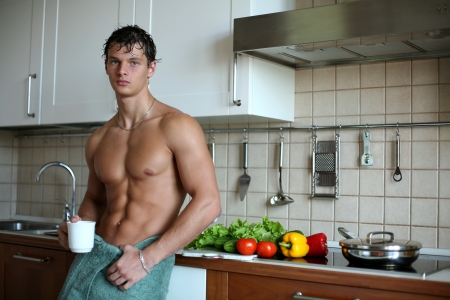 Young muscular sexy man eating his breakfast at the kitchenの写真素材