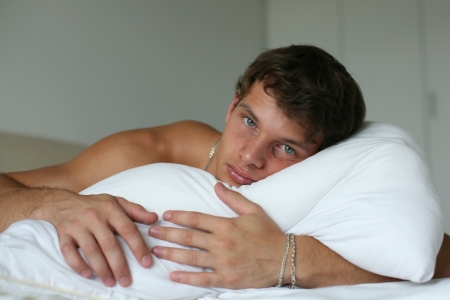 Young sexy man lying on a bedの写真素材