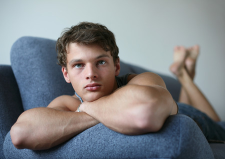 Young sexy man lying on a sofaの写真素材