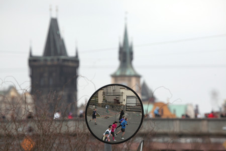 PRAGUE, CZECH REPUBLIC - APRIL 6, 2013: Convex mirror with the reflection of athletes running the Prague international marathon in Prague, Czech Republic. The Charles Bridge is seen in the background.のeditorial素材