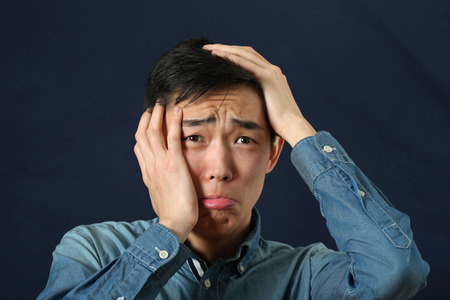 Disappointed young Asian man crying and looking sidewaysの写真素材