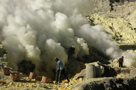 KAWAH IJEN, INDONESIA - AUGUST 9, 2011: Miners collect sulphur in the fumes of toxic volcanic gas at s the ulphur mines in the crater of the active volcano of Kawah Ijen, East Java, Indonesia.のeditorial素材