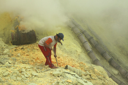 KAWAH IJEN, INDONESIA - AUGUST 10, 2011: Miner collects sulphur in the fumes of toxic volcanic gas at the sulphur mines in the crater of the active volcano of Kawah Ijen, East Java, Indonesia.のeditorial素材