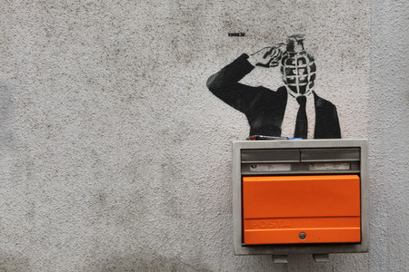 PRAGUE, CZECH REPUBLIC - NOVEMBER 11, 2012: Grenade-headed person blowing his head up depicted in the street graffiti next to the letter box in Prague, Czech Republic.のeditorial素材