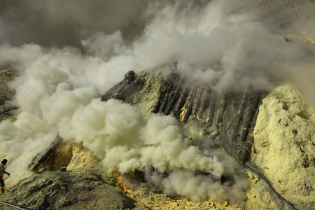 KAWAH IJEN, INDONESIA - AUGUST 8, 2011: Miner collects sulphur in the fumes of toxic volcanic gas at the sulphur mines in the crater of the active volcano of Kawah Ijen, East Java, Indonesia.のeditorial素材
