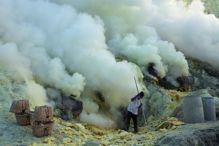 KAWAH IJEN, INDONESIA - AUGUST 9, 2011: Miner collects sulphur in the fumes of toxic volcanic gas at the sulphur mines in the crater of the active volcano of Kawah Ijen, East Java, Indonesia.のeditorial素材