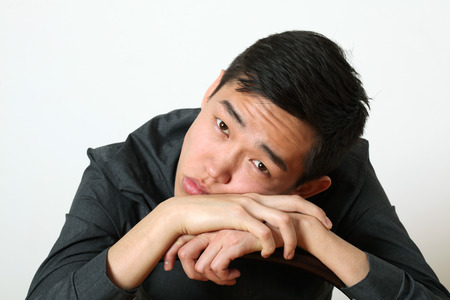 Thoughtful young Asian man looking at camera.の写真素材