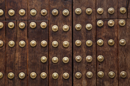 Old wooden gate fixed with large brass rivets in Cordoba, Andalusia, Spain.の写真素材