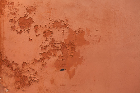 Old terracotta painted stucco wall with chipped paint. Background texture.の写真素材