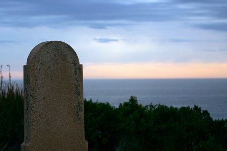 A gravestone overlooking the ocean at dawn