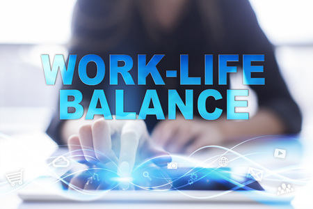 Woman is using modern tablet pc, presssing on touch screen and selecting "Work-life balance".の写真素材