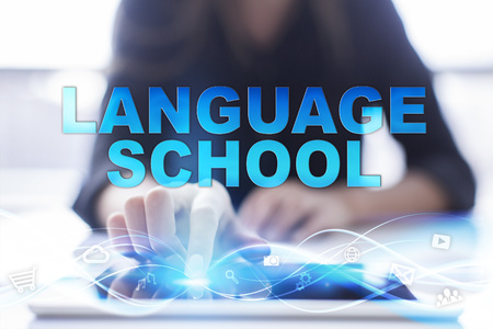 Woman is using modern tablet pc, presssing on touch screen and selecting "Language school".の写真素材