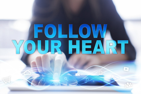 Woman is using modern tablet pc, presssing on touch screen and selecting "Follow your heart".の写真素材