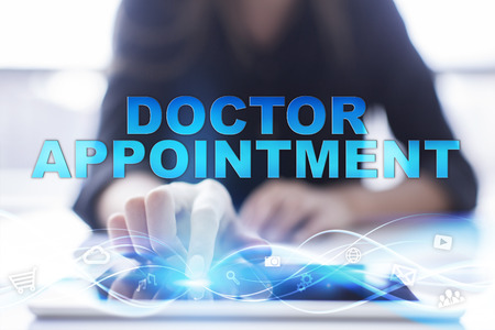 Woman is using modern tablet pc, presssing on touch screen and selecting "Doctor appointment".の写真素材