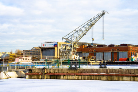 ST PETERSBURG, RUSSIA-MARCH 31, 2021: Container crane in the Admiralty Shipyards near ice covered Neva river. Industry and ships.のeditorial素材
